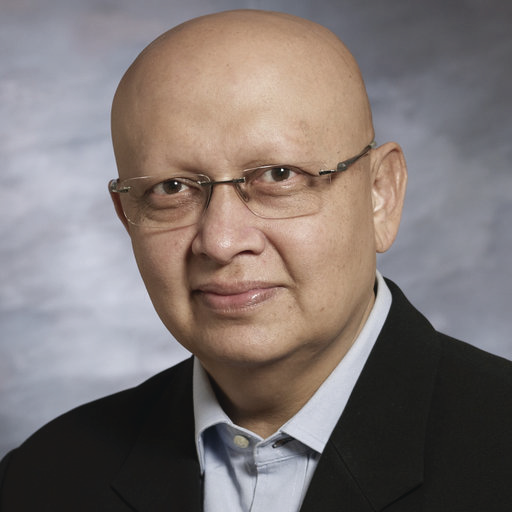 Portrait photo of Dr Sanjay Desai, elderly man with glasses and bald head